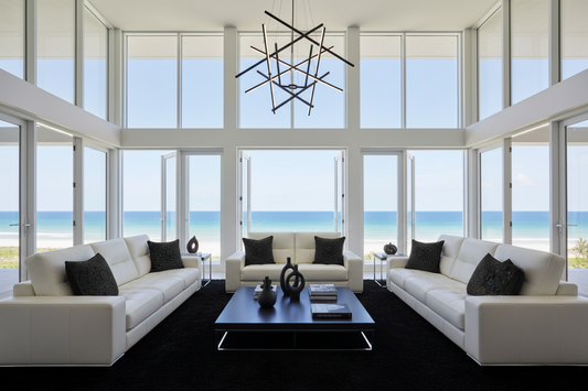 Modern living room with white sofas, black coffee table, and ocean view.