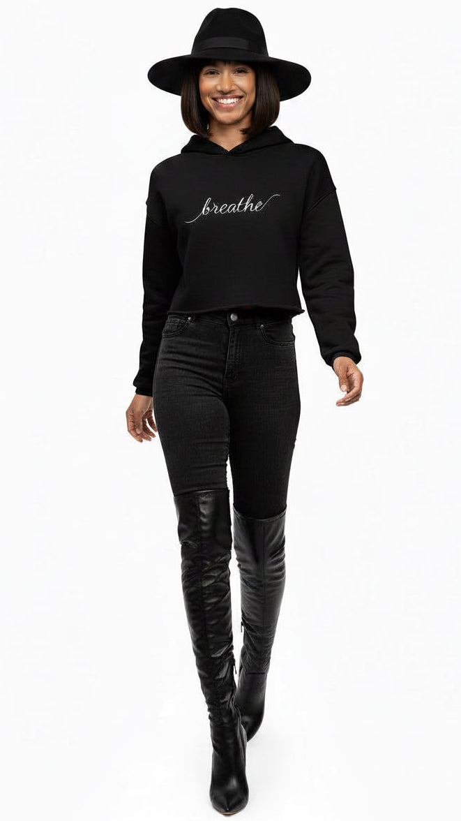 Woman wearing a KhuKhuZ black hoodie with 'breathe' text and black pants on a white background