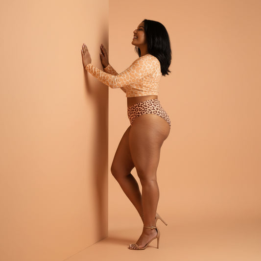 Woman wearing an peach fuzz patterned long-sleeve crop top and beige high-waisted bikini against a peach fuzz wall.
