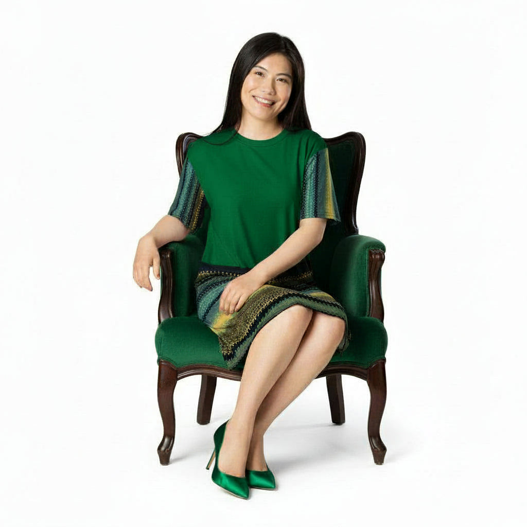 Woman wearing a green dress with patterned sleeves sitting n an elegant green chair