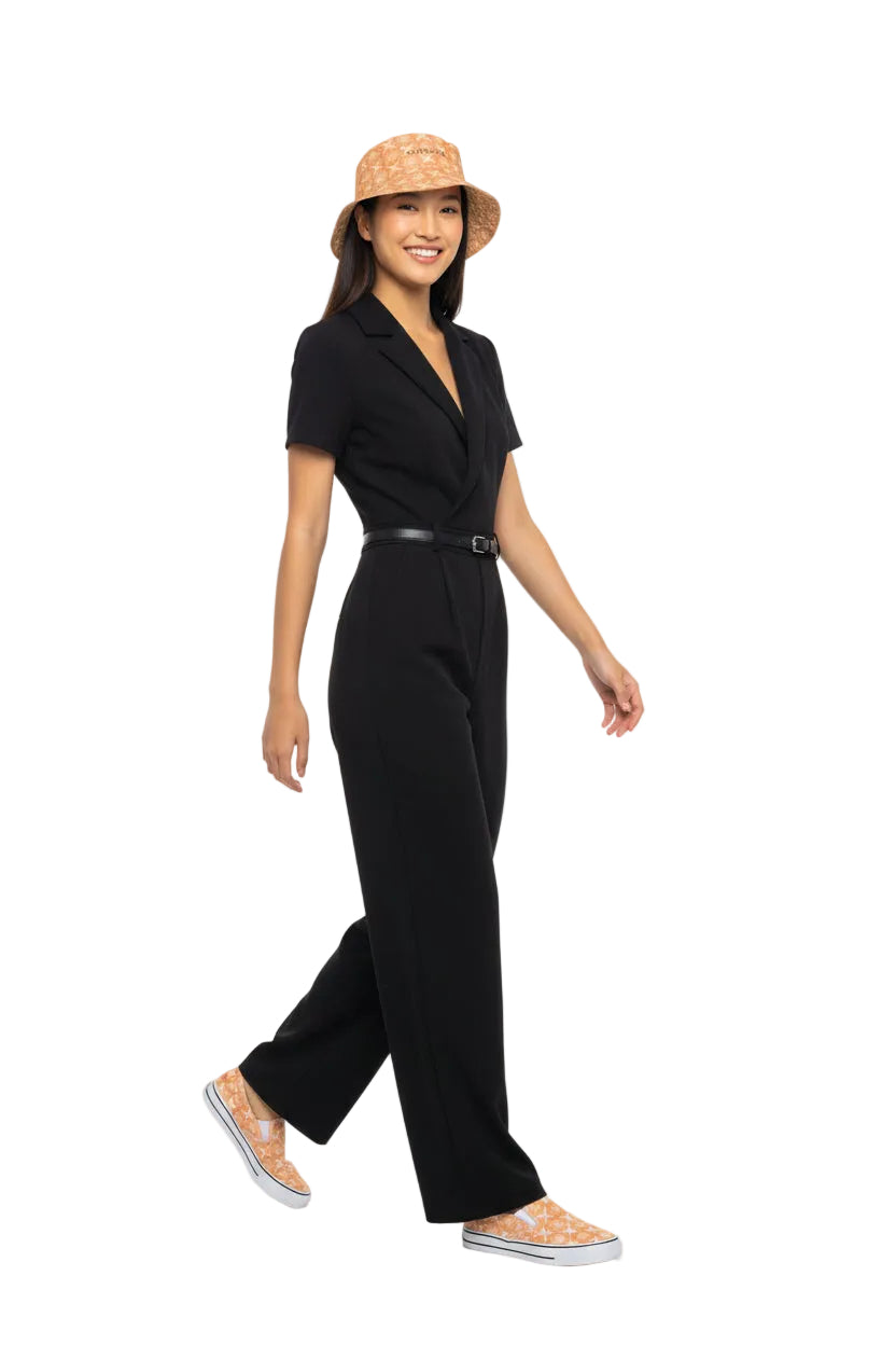Woman wearing a black jumpsuit and KhuKhuZ peach fuzz bucket hat on a white background