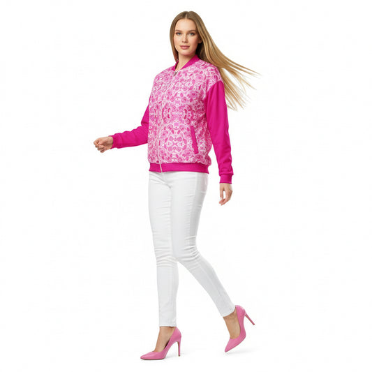 A person wearing a pink and floral unisex bomber jacket with a hood, paired with blue jeans and white sneakers.