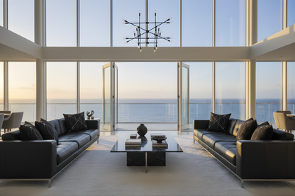 Throw cushions monochrome, Modern living room with black leather sofas, a glass coffee table, and large windows overlooking the ocean.