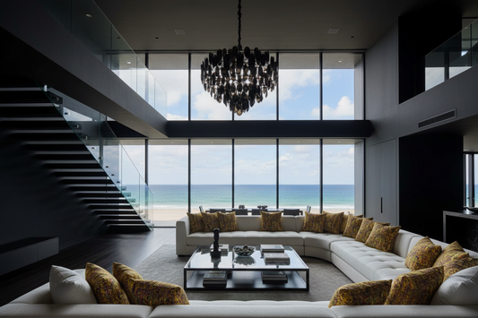 Modern living room with a large sectional sofa, coffee table, and ocean view, with colourful cushion deco