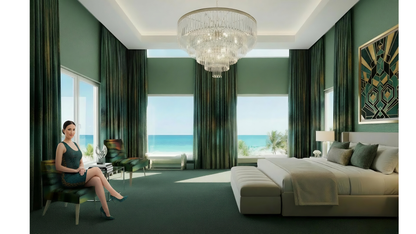 Luxurious bedroom with a woman sitting on a chair, large windows with ocean view, and a chandelier.