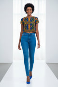 Woman wearing a colorful patterned crop top and blue jeans on a white background