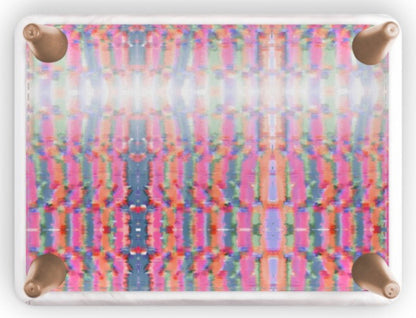 A square side table featuring a vibrant, multicolor abstract symmetrical pattern in pink, blue, green, and yellow, with four metallic rose gold corner brackets on a white background.
