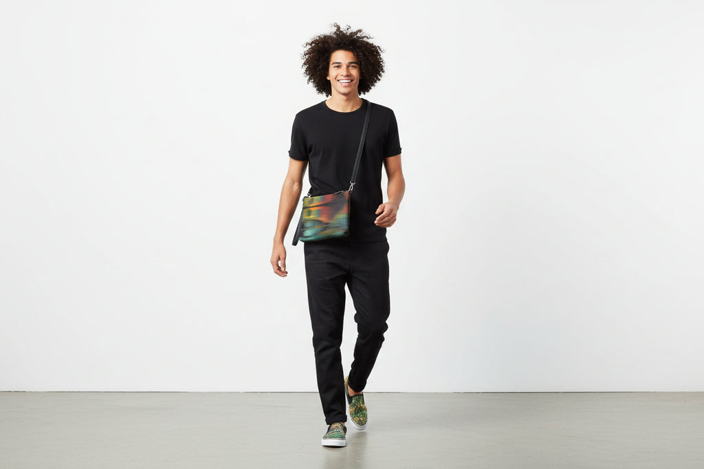 Man walking with a colorful crossbody bag against a white background