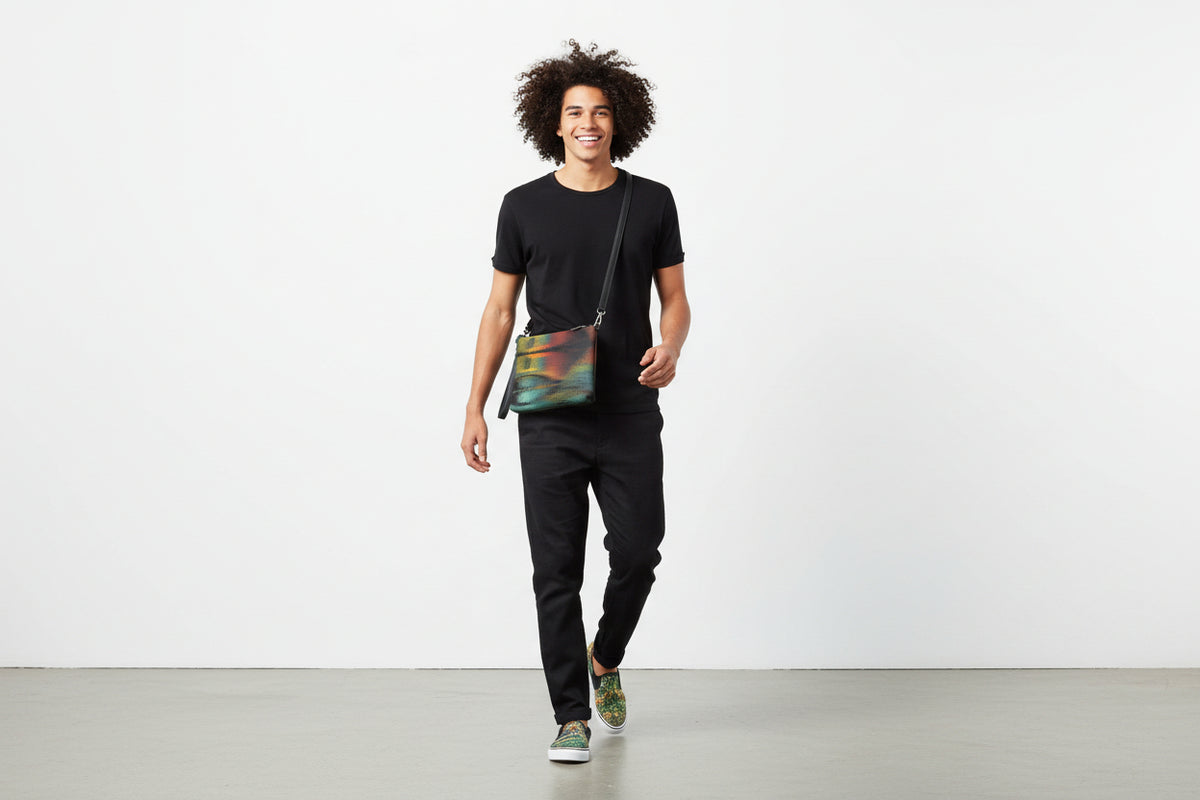 Man walking with a colorful crossbody bag against a white background