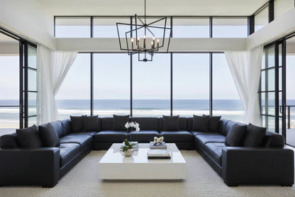 Modern living room with black sectional sofa, white coffee table, and large windows overlooking an ocean view, with BP Interiors monochrome cushions small circles print design