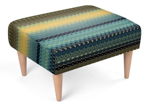 A square upholstered footstool with tapered light wood legs, featuring a striped pattern of yellow, teal, blue, and dark navy with intricate lace-like details.