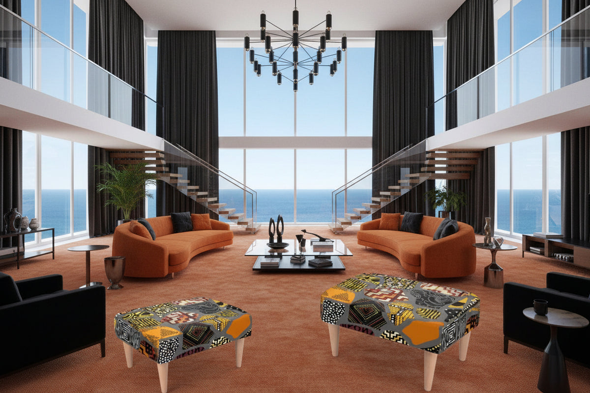 A square upholstered footstool with a bold geometric and tribal-inspired pattern in orange, yellow, black, white, and gray, supported by four light wood legs on a white background.