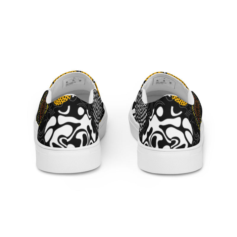 A pair of low-top slip-on sneakers shown from the back, featuring a bold black and white abstract pattern on the back panels, a textured black and white side panel, and a yellow dotted pattern on the heel, set against a plain white background.