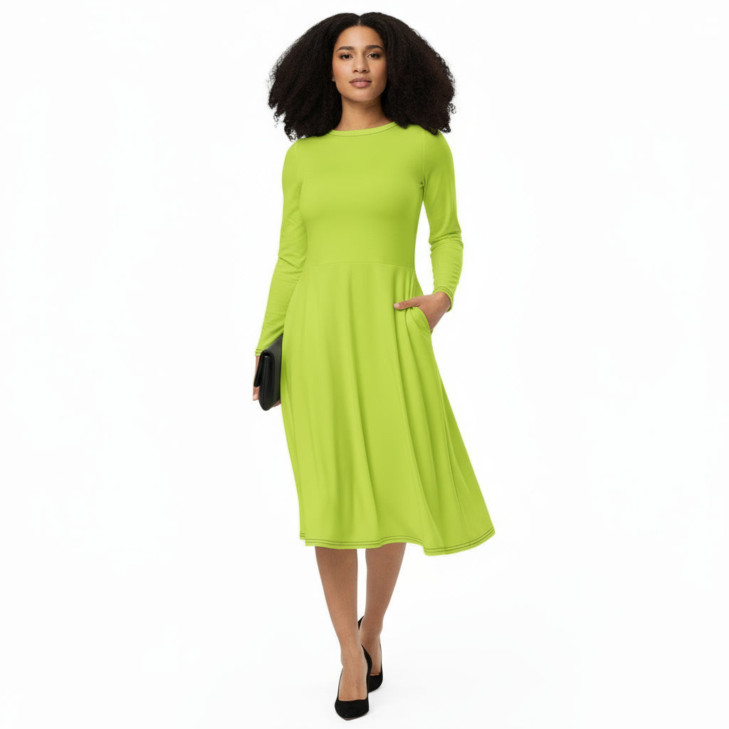 A woman standing and smiling, wearing a neon green, long sleeve, midi dress with a flared bottom. She is also wearing black court shoes.