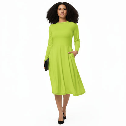 A woman standing and smiling, wearing a neon green, long sleeve, midi dress with a flared bottom. She is also wearing black court shoes.