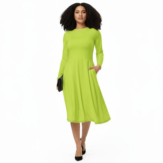 A woman standing and smiling, wearing a neon green, long sleeve, midi dress with a flared bottom. She is also wearing black court shoes.