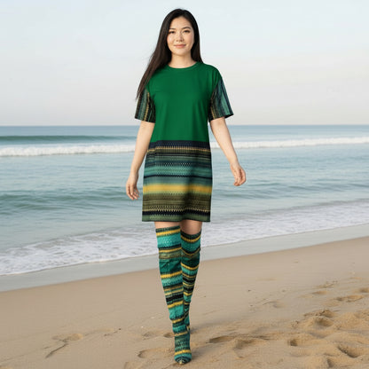 Woman wearing a green dress with a patterned sleeve standing on a beach.