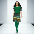 Woman wearing a green dress with patterned sleeves and hem on a white background, dancing and laughing