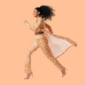 Woman wearing a peach fuzz outfit with a long coat on a white background.