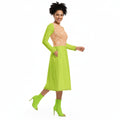 Woman wearing a bright green dress with long sleeves and a patterned top underneath on a white background.