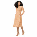 Woman wearing KhuKhuZ peach fuzz patterned dress on a white background