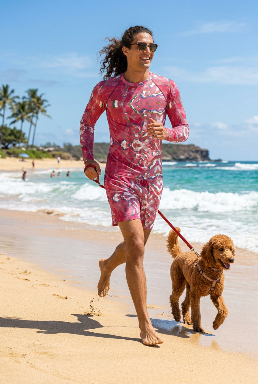 A man wearing a long-sleeve athletic rash guard with a pink, red, and white abstract pattern, paired with matching swim trunks. 