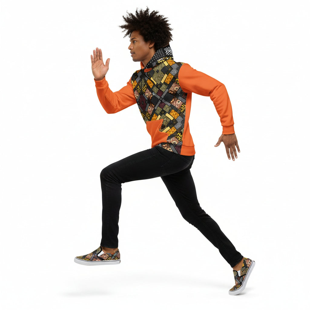 Person wearing an orange long-sleeve shirt with a patterned design, black pants, and patterned shoes on a white background