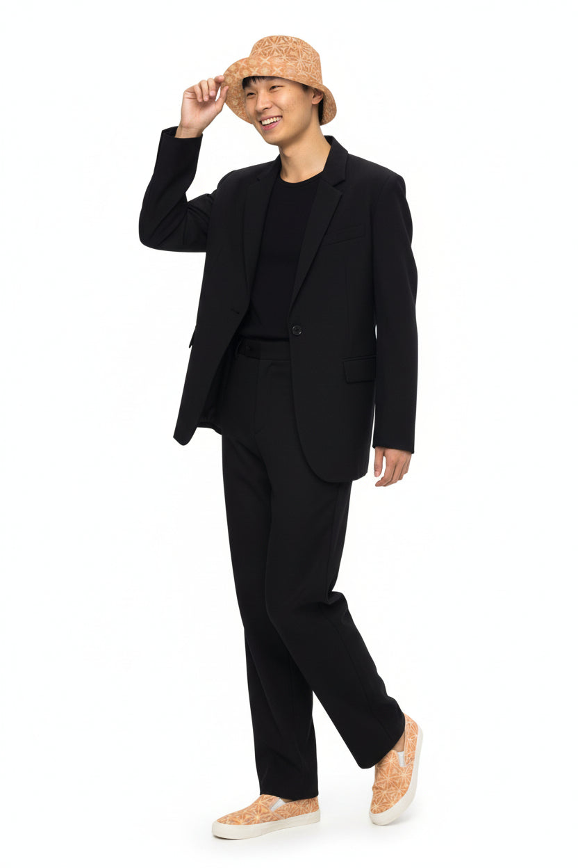 Person wearing a black suit with a KhuKhuZ peach fuzz bucket hat on a white background
