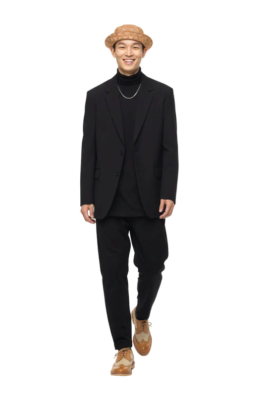 Man wearing a black suit with a KhuKhuZ peach fuzz bucket hat on a white background