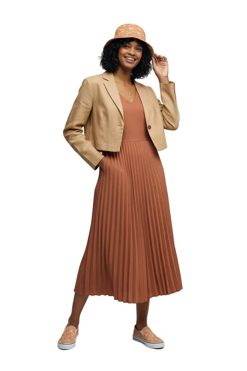 Woman wearing a beige blazer, rust pleated dress, and matching hat on a white background