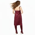 Woman wearing a burgundy satin slip dress on a white background