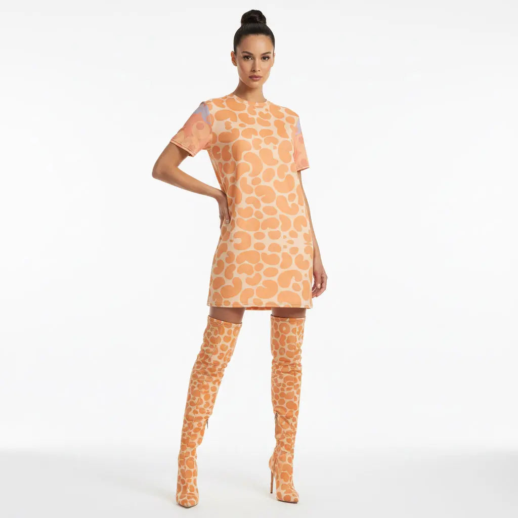Woman wearing a giraffe-patterned dress and matching thigh-high boots on a white background