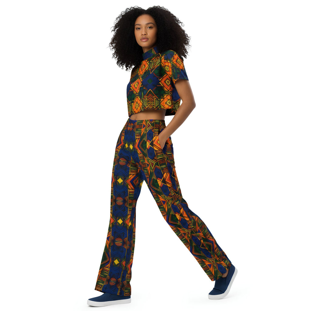 Woman wearing colorful patterned pants and a white crop top on a white background