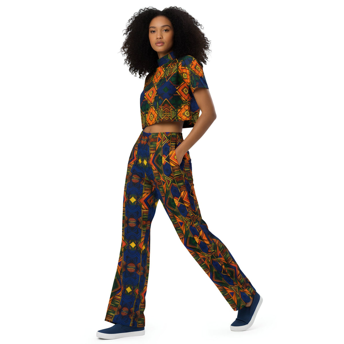 Woman wearing colorful patterned pants and a white crop top on a white background
